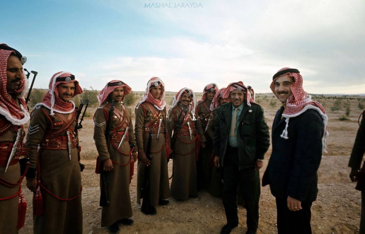 Prince Muhammad bin Talal 1970 — ‏الأمير محمد بن طلال رحمه الله عام 1970م.
‏يظهر الأمير في مقدمة الصورة، مرتدياً سترة رسمية والشماغ الأحمر المهدب. 
‏محاط بمجموعة من قوات البادية الملكية الذين يرتدون الزي الكاكي الطويل. (1970)